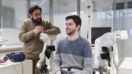 Silvestro Micera (à gauche) et Leonardo Pollina avant une expérience avec le troisième bras en réalité virtuelle. © 2023 EPFL / Alain Herzog, CC-BY-SA