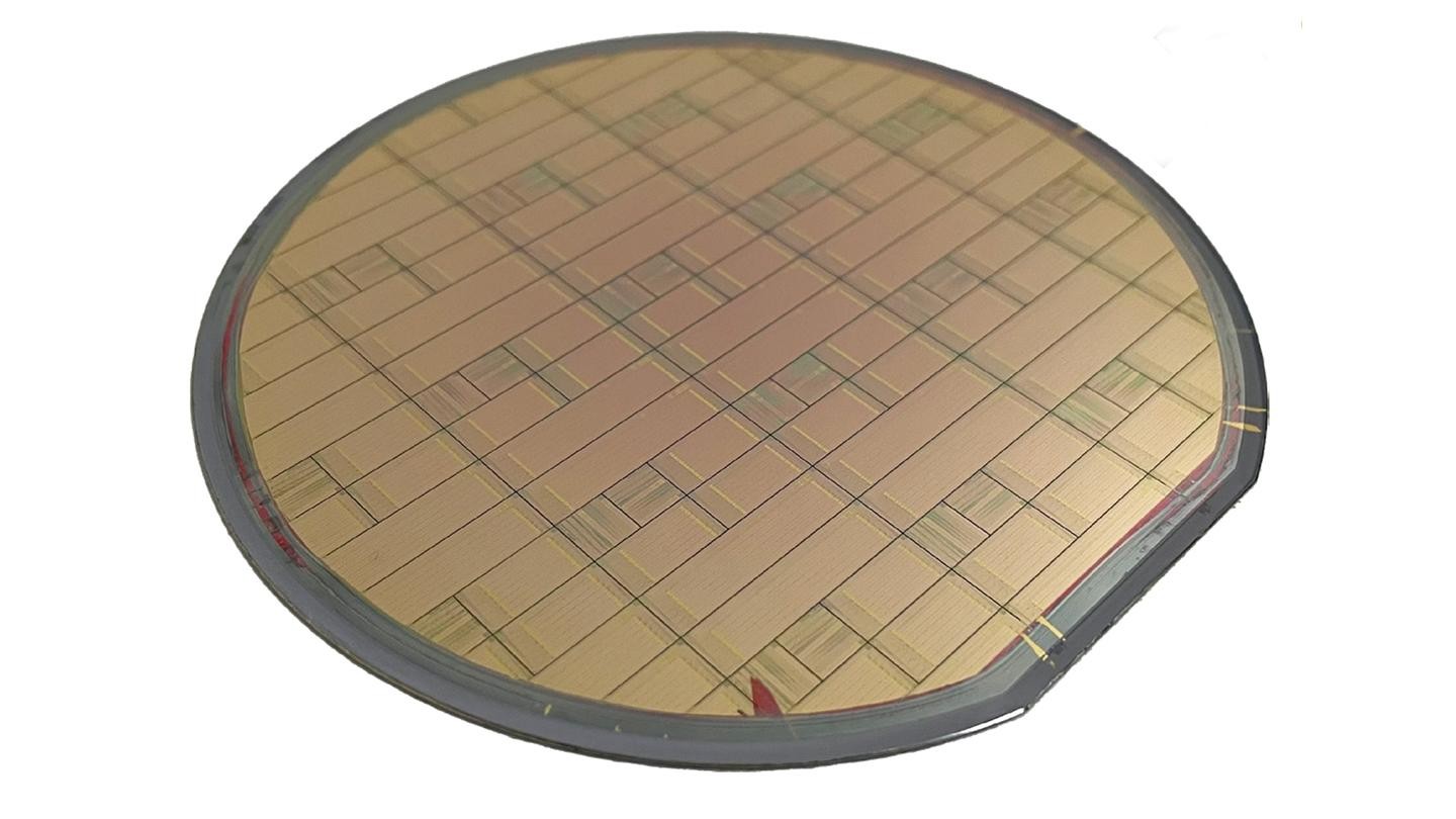 Photographie d'une plaquette de 100 mm fabriquée hébergeant des centaines de modulateurs en tantalate de lithium damascène en cuivre. Crédit : Lin et al 2026.