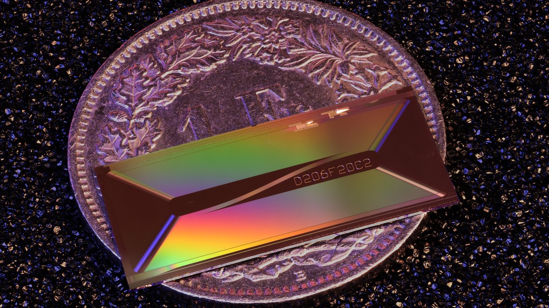 Placed on a 1 CHF coin for scale, EPFL's photonic chip shows how a laser architecture once confined to table-top systems can be shrunk to the millimeter scale. ©2026 EPFL/Zheru Qiu