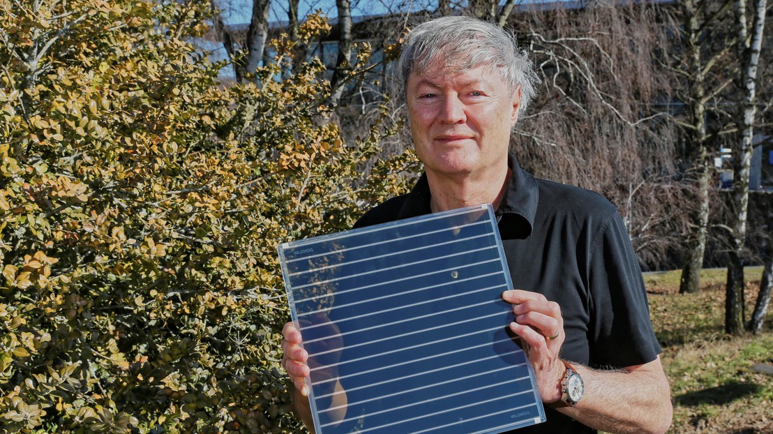 Professor Michael Grätzel holding up a dye-sensitized solar cell. Credit: Alain Herzog/EPFL