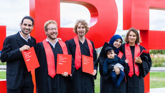 The new graduates pose in front of the EPFL logo © 2019 Jamani Caillet