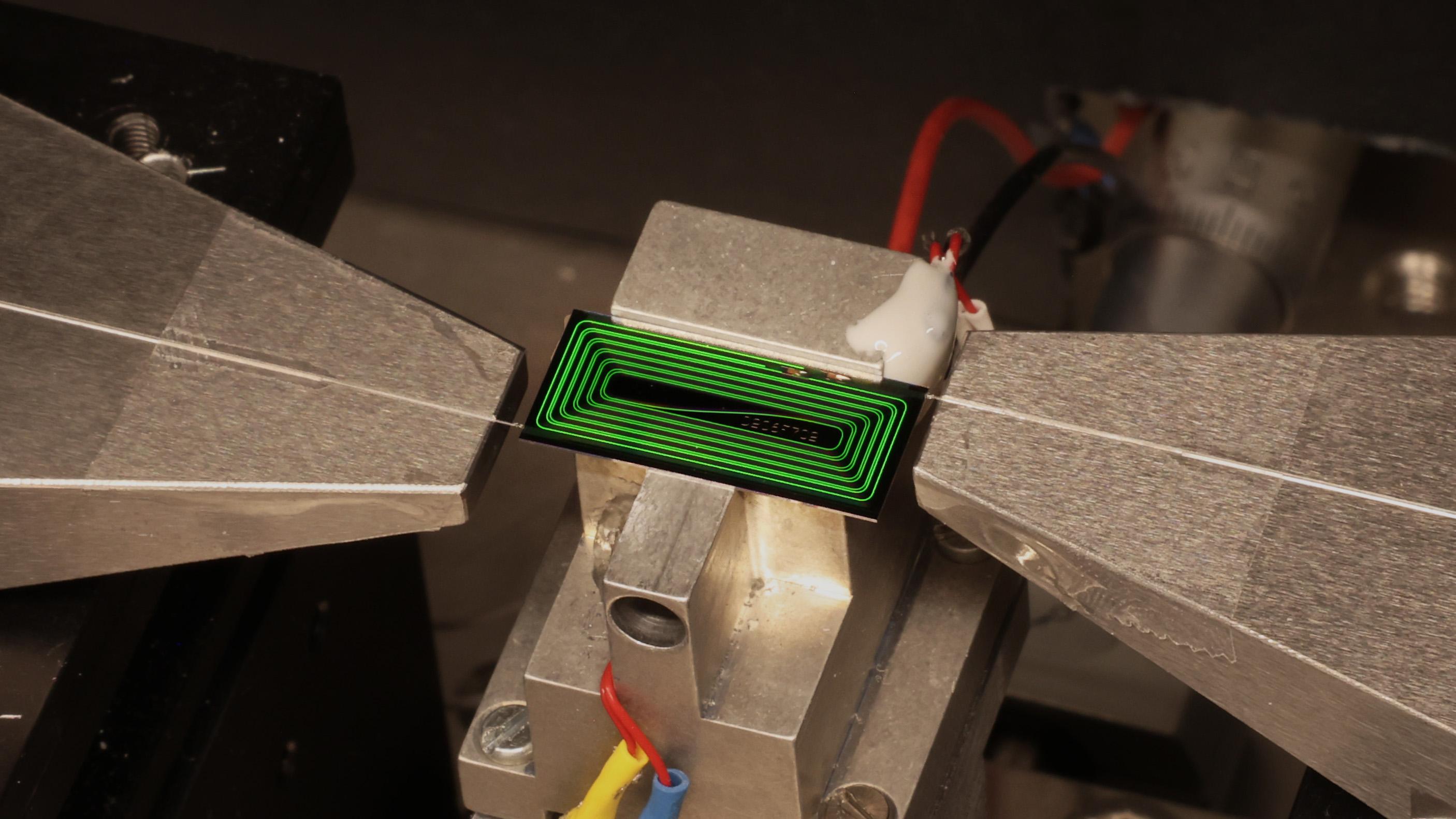 EPFL's chip-based ultrafast laser operating in the laboratory test setup. The device produces extremely short laser pulses directly on a photonic chip. Credit: Zheru Qiu/EPFL